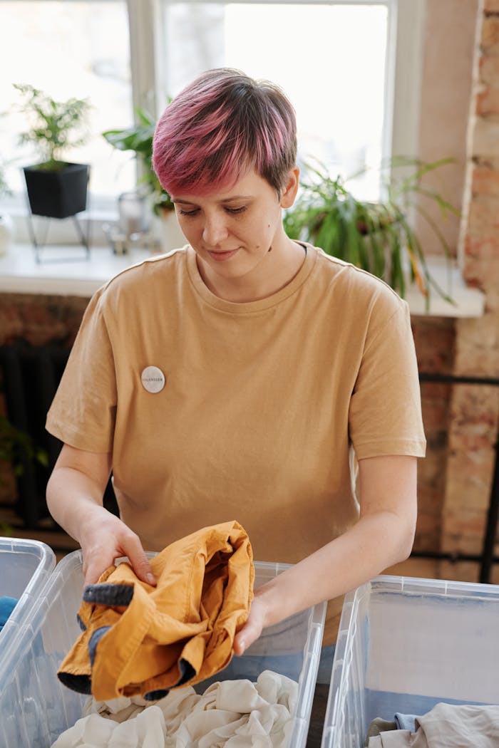 The Art of Drawing Readers In: Your attractive post title goes here A woman with pink hair sorts clothing as a volunteer in an indoor setting.