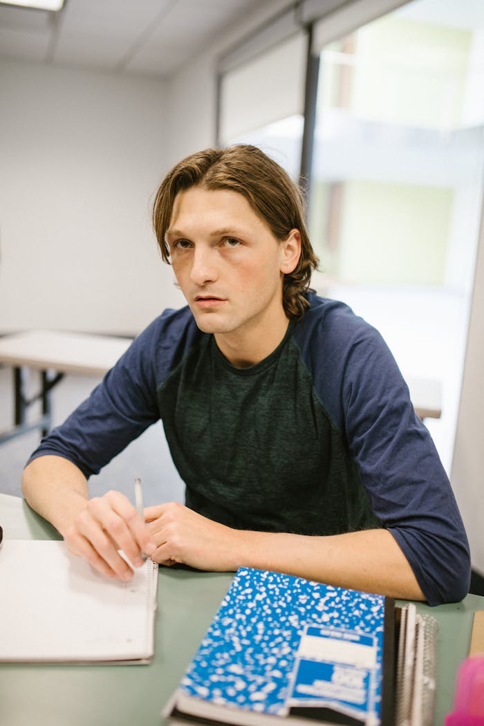 College student sitting at a desk, focused and studying in a classroom setting.